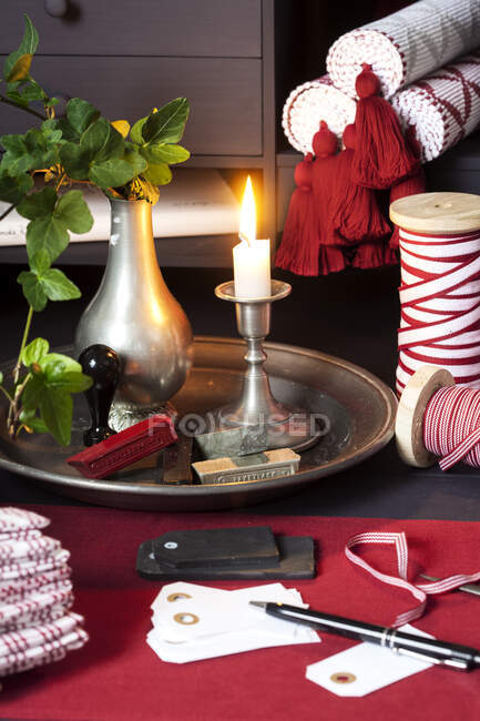 Geschenketiketten und Schleife bei Kerze auf Tablett — Stockfoto