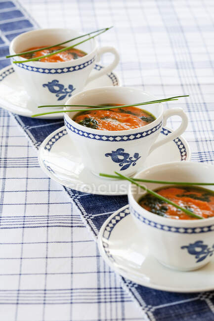 Cups of gazpacho on tablecloth — Photo de stock
