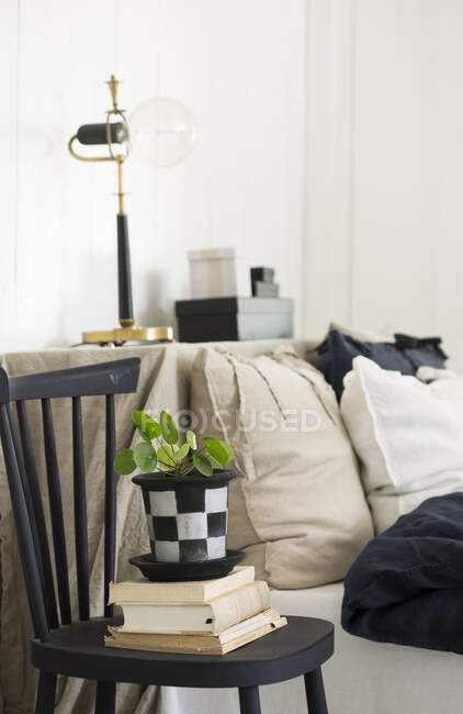 Potted plant and books on chair by bed — Stock Photo