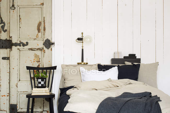 Ліжко за вивітреними дверима і рослина — стокове фото