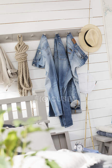 Jeans, cuerda y sombrero de paja colgando de ganchos - foto de stock