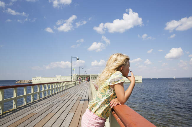 Girl leaning on pier railing — Photo de stock