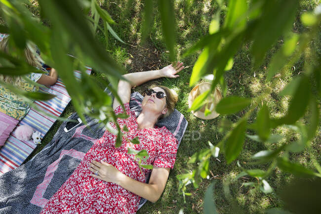 High angle view of woman lying on picnic blanket - foto de stock