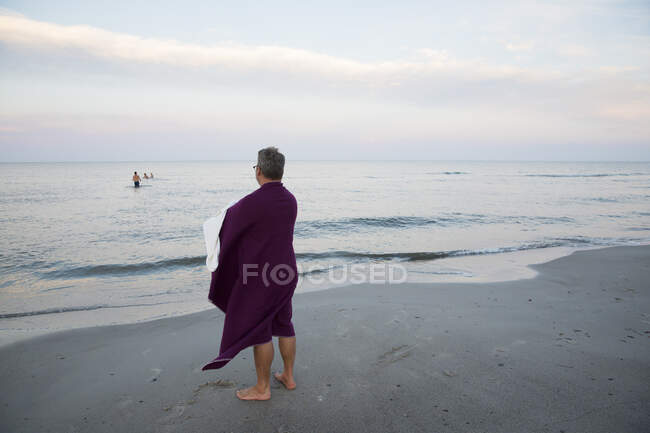 Man wrapped in towel standing on beach — Fotografia de Stock
