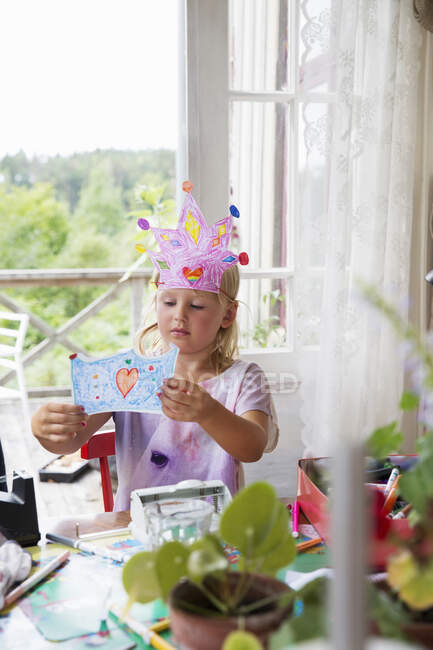 Girl playing and making paper crown — Stock Photo