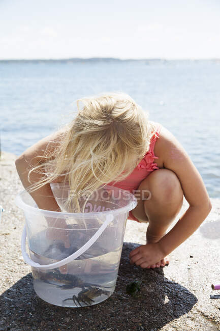 Girl crouching by bucket with crabs — Foto stock