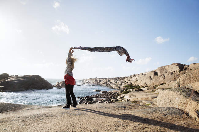 Mädchen mit Schal steht am windigen Strand — Stockfoto