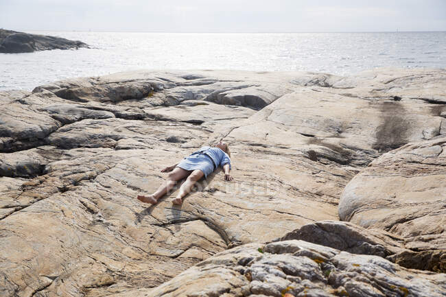 Mulher deitada em rochas na praia — Fotografia de Stock