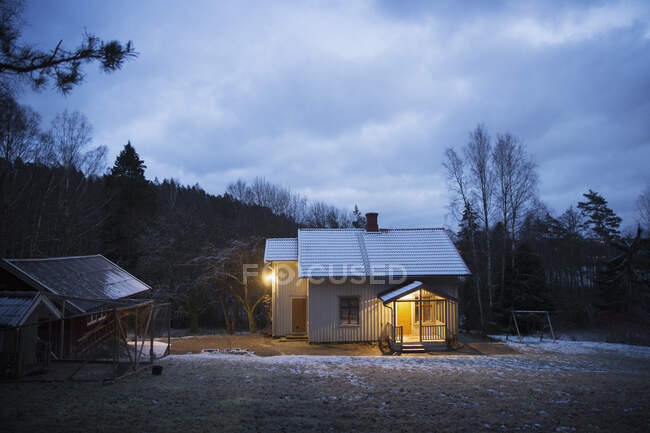 Casa iluminada por la noche por el bosque - foto de stock