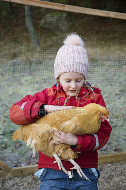 Девушка в теплой одежде ласкает курицу — стоковое фото
