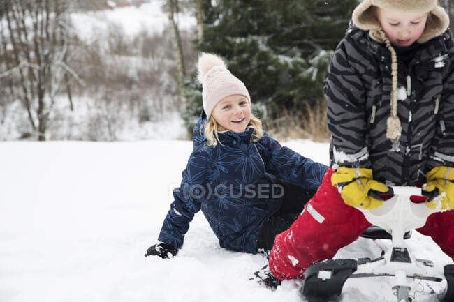 Girls playing with toboggan at ski field — Stock Photo
