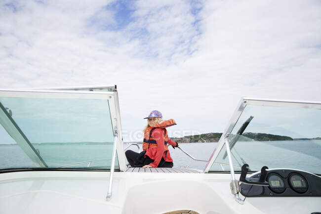 Girl in life jacket sitting on boat — Stockfoto