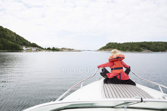 Девушка в спасательной куртке сидит на лодке — стоковое фото
