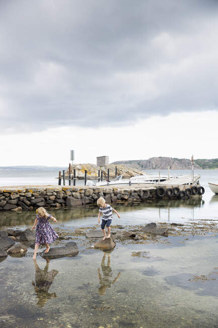 Children walking on rocks in sea — Stock Photo