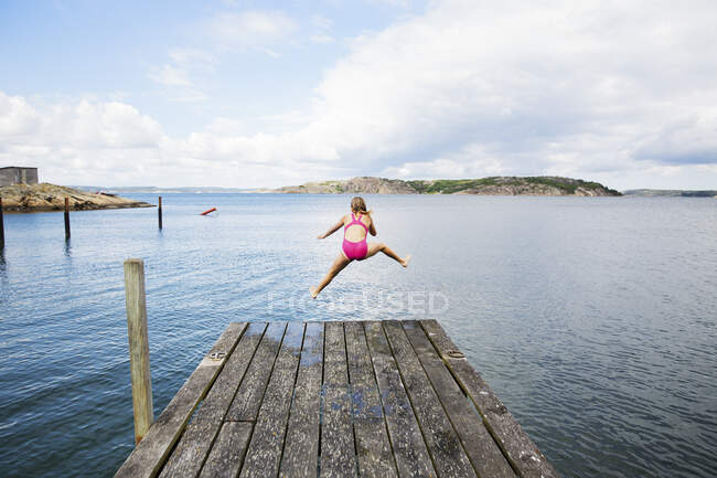 Girl diving into sea from jetty — Stockfoto