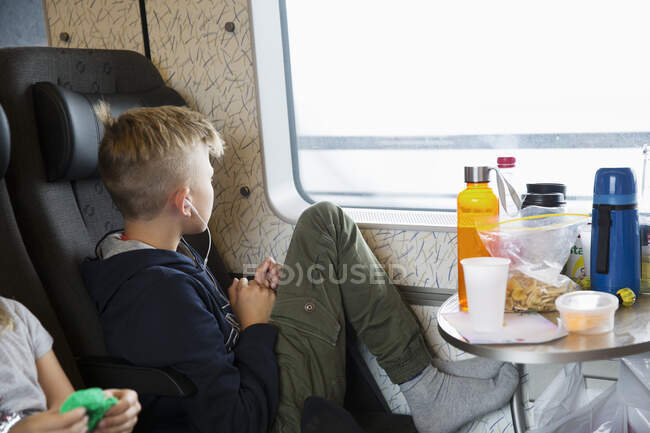 Boy sitting by window of train — Stockfoto