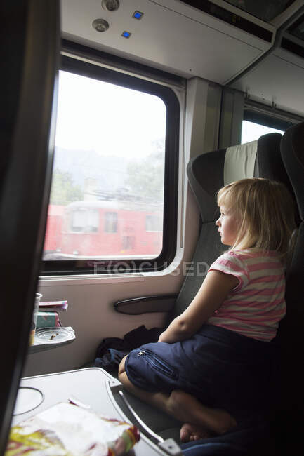 Девушка сидит в поезде и смотрит в сторону — стоковое фото