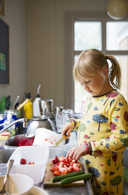Fille coupe des fraises dans la cuisine — Photo de stock