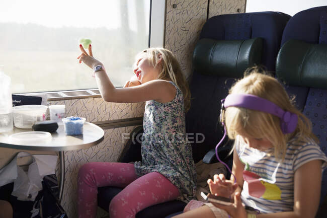 Girls sitting on moving train - foto de stock
