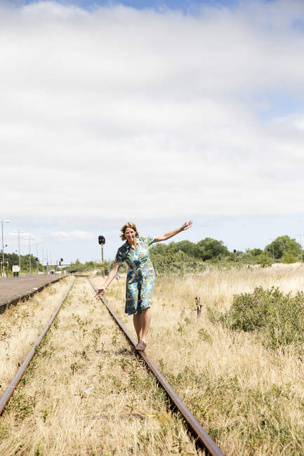 Lächelnde Frau balanciert auf Bahngleisen — Stockfoto