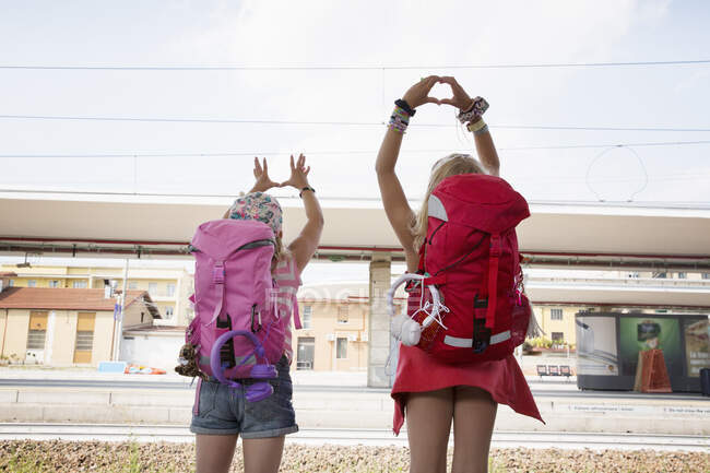 Chicas con mochilas en la estación de tren - foto de stock