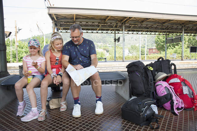 Family sitting at train station — Stockfoto