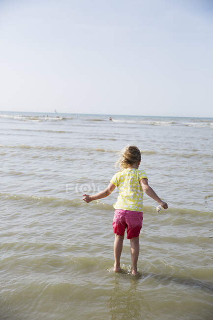 Дівчина стоїть у воді на пляжі — стокове фото