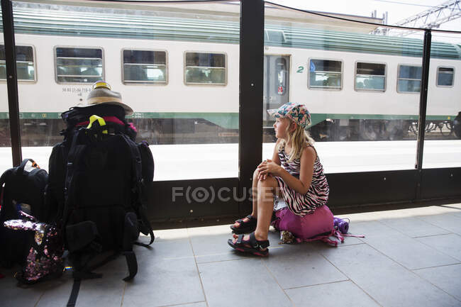 Menina sentada no saco na estação de trem — Fotografia de Stock