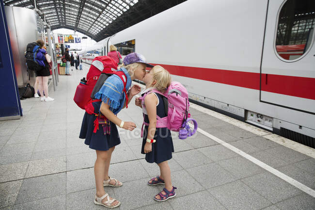 Sisters kissing at train station — Stockfoto