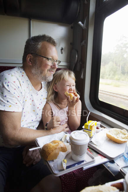 Père et fille prennent le petit déjeuner en train — Photo de stock