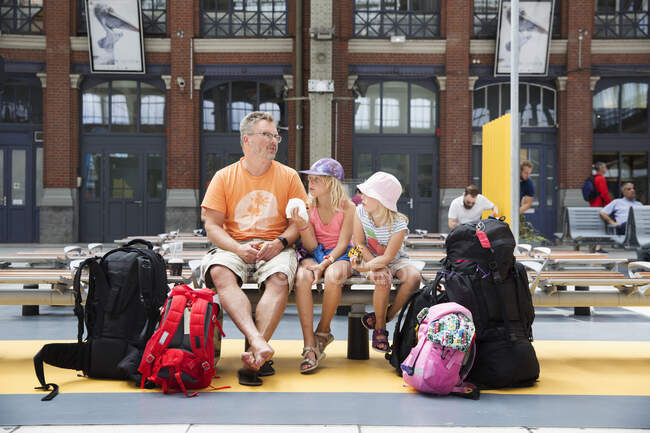 Family sitting on bench at train station — Stockfoto