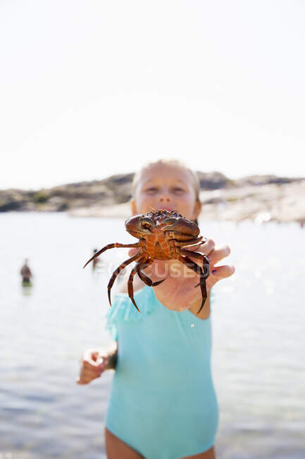 Girl in swimsuit holding crab — Stockfoto