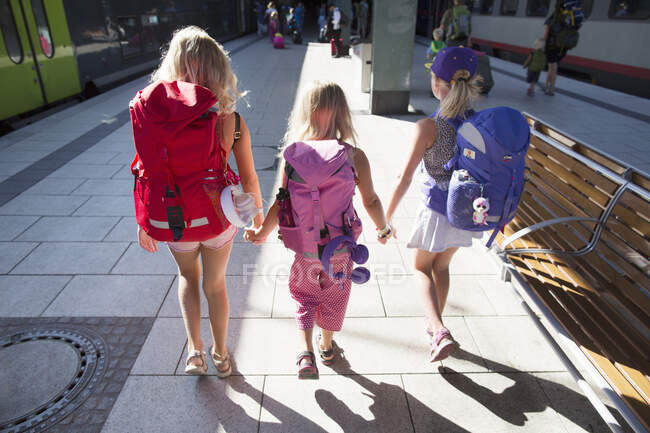 Sisters holding hands and walking at train station — Fotografia de Stock