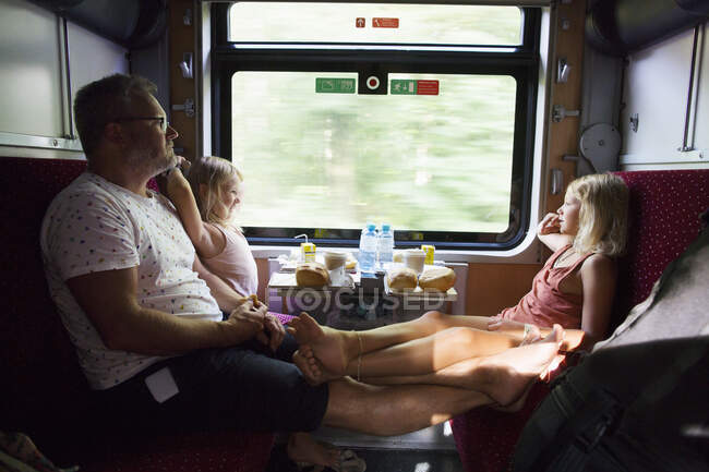 Семья сидит у окна в поезде — стоковое фото