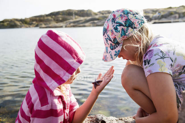 Sisters looking at starfish by sea — Foto stock