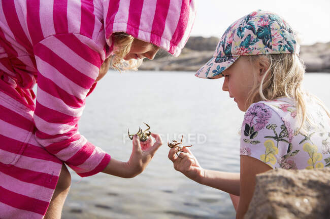 Sisters holding crabs by sea — Photo de stock