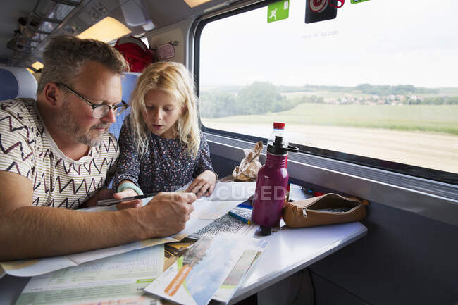 Father and daughter looking at map on train — Foto stock