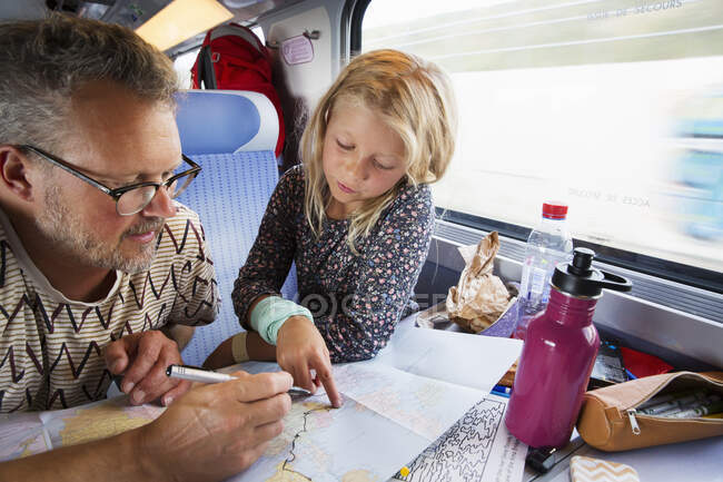 Отец и дочь смотрят на карту в поезде — стоковое фото