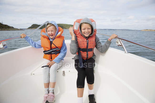 Улыбающиеся девушки в спасательных жилетах сидят на лодке — стоковое фото