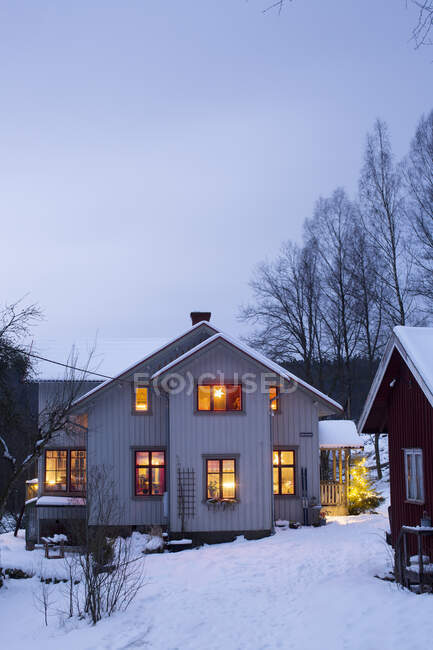 Иллюминированный дом зимой вечером — стоковое фото