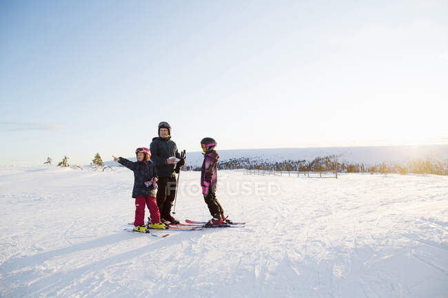 Family standing in snow while skiing — Stockfoto