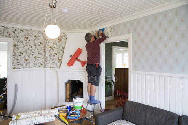 Man applying wallpaper in house — Foto stock