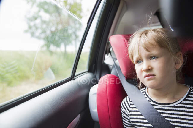 Fille assise dans la voiture regardant loin — Photo de stock