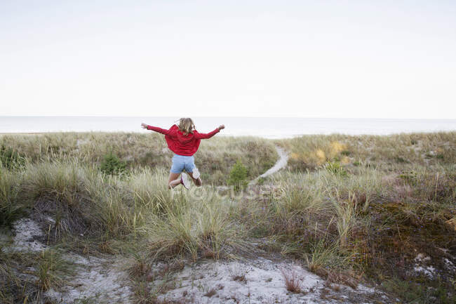 Girl jumping on sand dunes — Stock Photo
