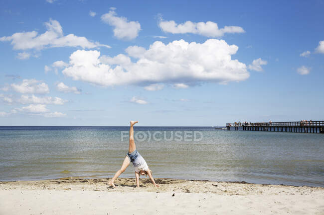 Menina fazendo cartwheel na praia — Fotografia de Stock