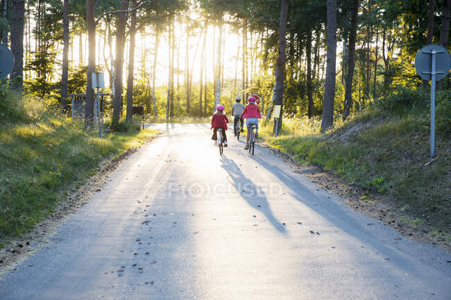 Family riding bicycles on road - foto de stock