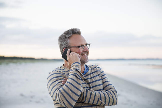 Uomo che parla su smart phone in spiaggia — Foto stock