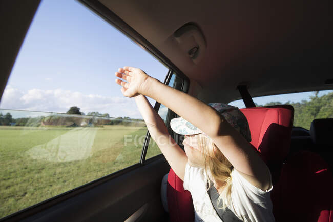 Girl with raised arms in car - foto de stock