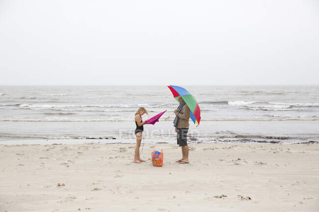 Father and daughter standing on beach — Stockfoto