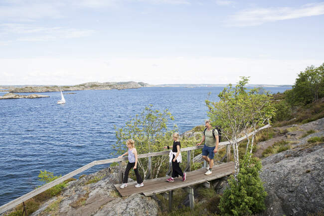 Family hiking over bridge by sea — Photo de stock